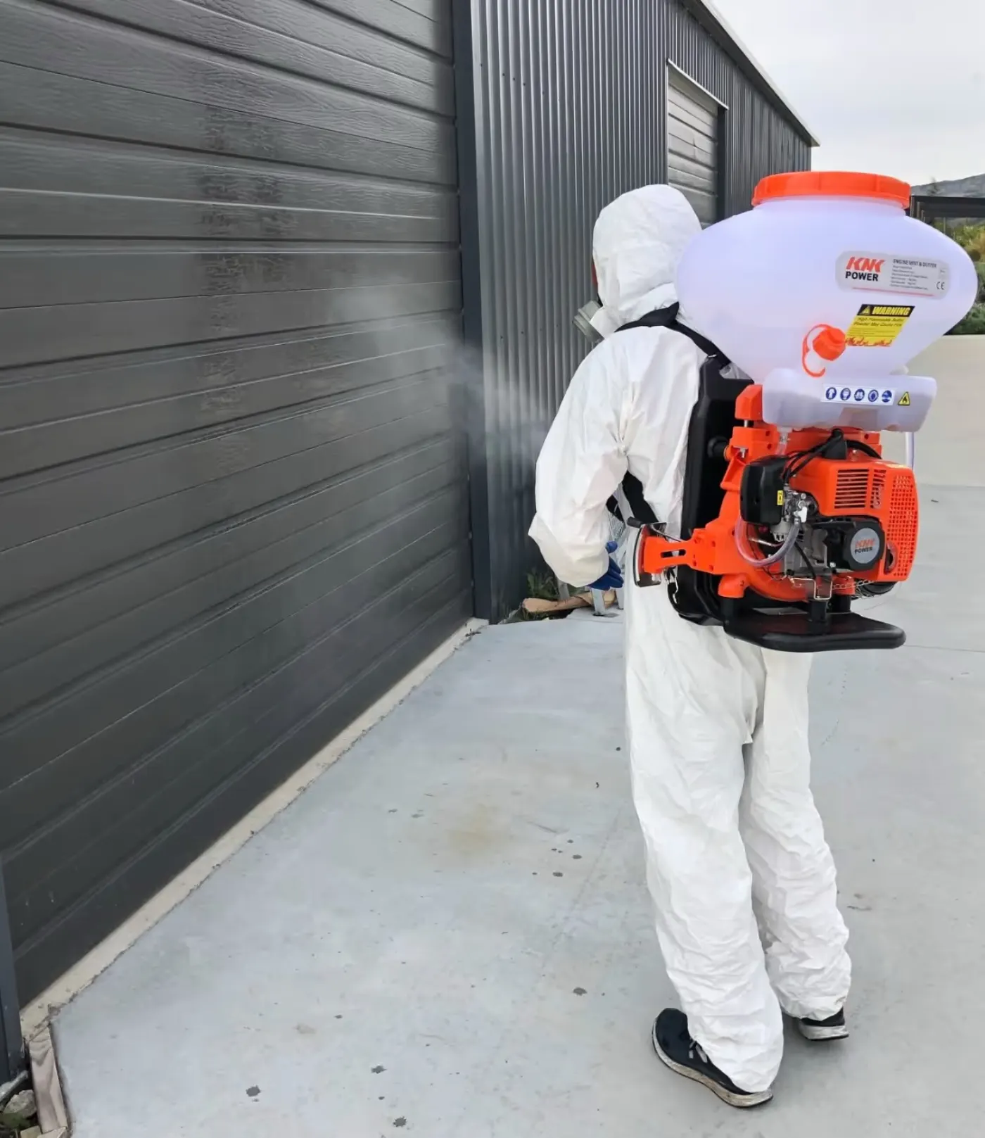 Technician applying a pest treatment outside a building